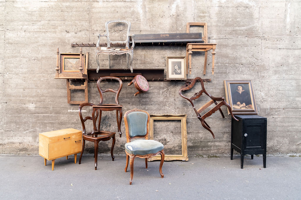 Vintage-Stühle, Rahmen und ein Holzkoffer vor einer Betonwand